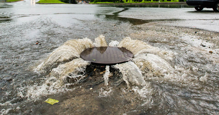 Regenwasser dringt aus einem Gulli nach oben
