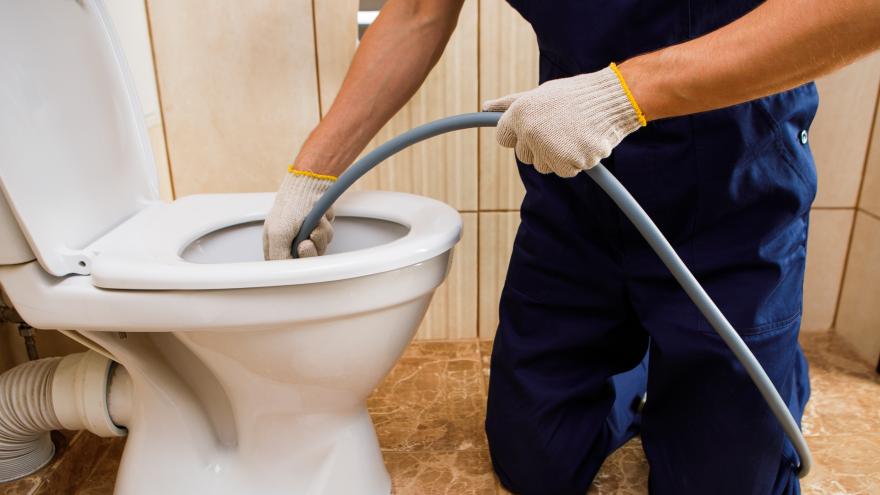 Handwerker reinigt Toilette mit Schlauch