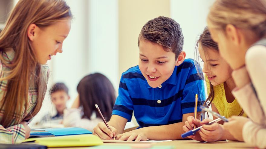Kinder sitzen am Tisch und machen eine Gruppenarbeit